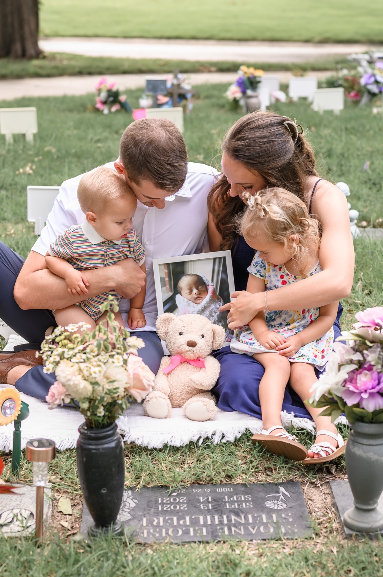 A family at a grave site with flowers