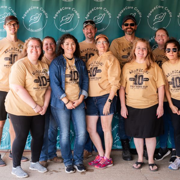 Agape_team_posing_together_wearing_similar_shirts_at_an_event