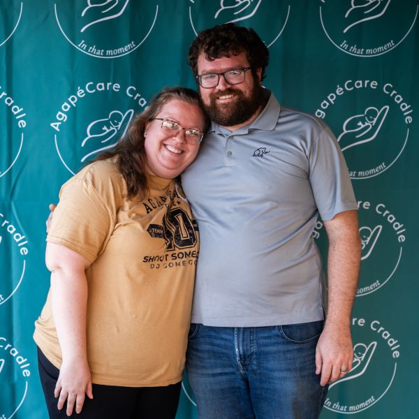 Couple_hugging_at_event_with_blue_backdrop