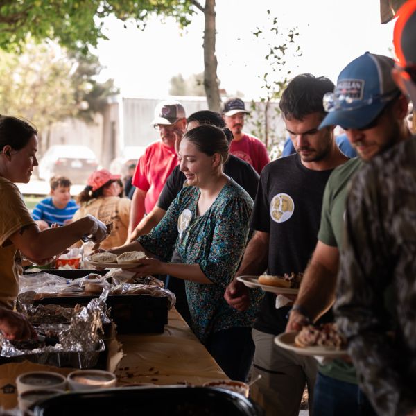 Food_table_at_outdoor_event_with_people_enjoying_meal_together
