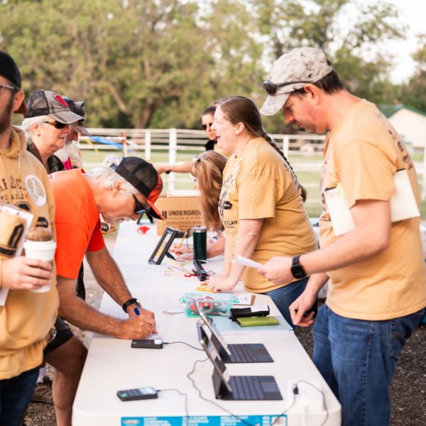 Group_of_people_gathered_around_table_in_outdoor_setting