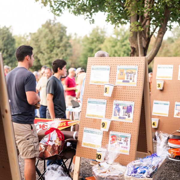 Man_standing_at_outdoor_raffle_with_poster_board