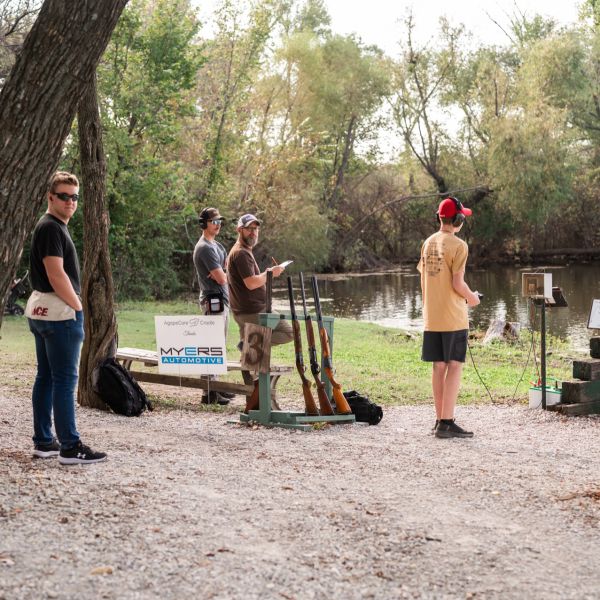 Men_with_sporting_clay_near_body_of_water