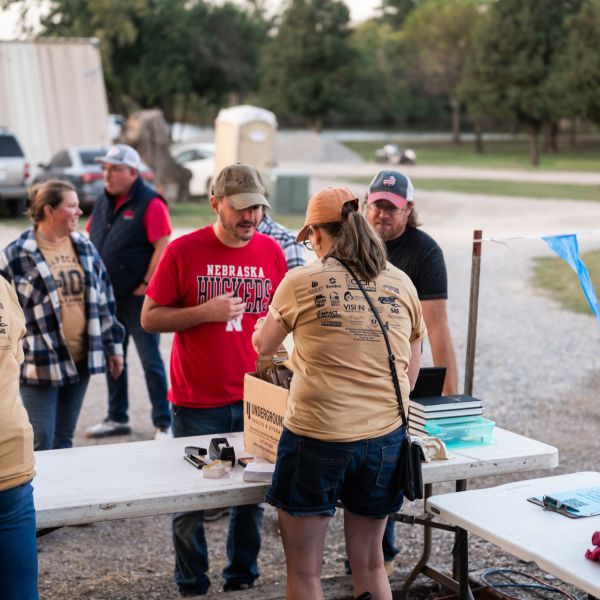 People_standing_around_tables_with_food_and_items_to_purchase