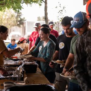 Food_table_at_outdoor_event_with_people_enjoying_meal_together
