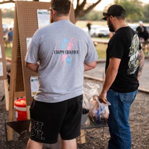 Men_at_outdoor_event_studying_information_board